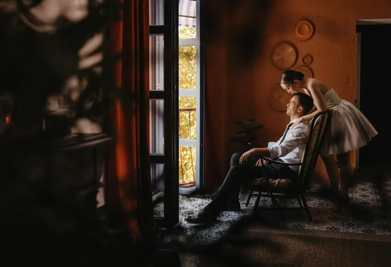 Cuplu lângă fereastra înaltă, într-un salon cu pereți teracotă