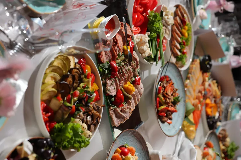 Platouri cu friptură feliată, legume și gustări colorate pe masa festivă